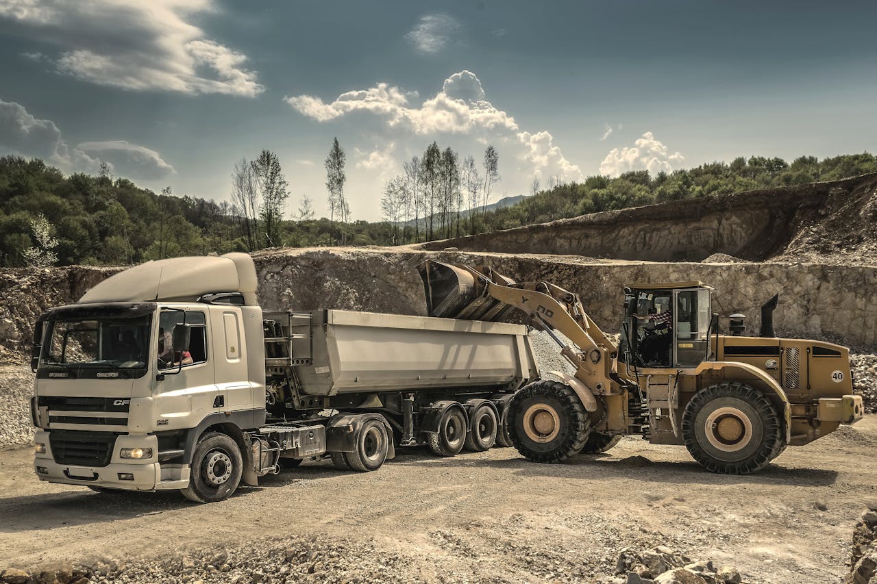 about-01 Excavator and truck working together in a quarry, showcasing industrial equipment and operations.