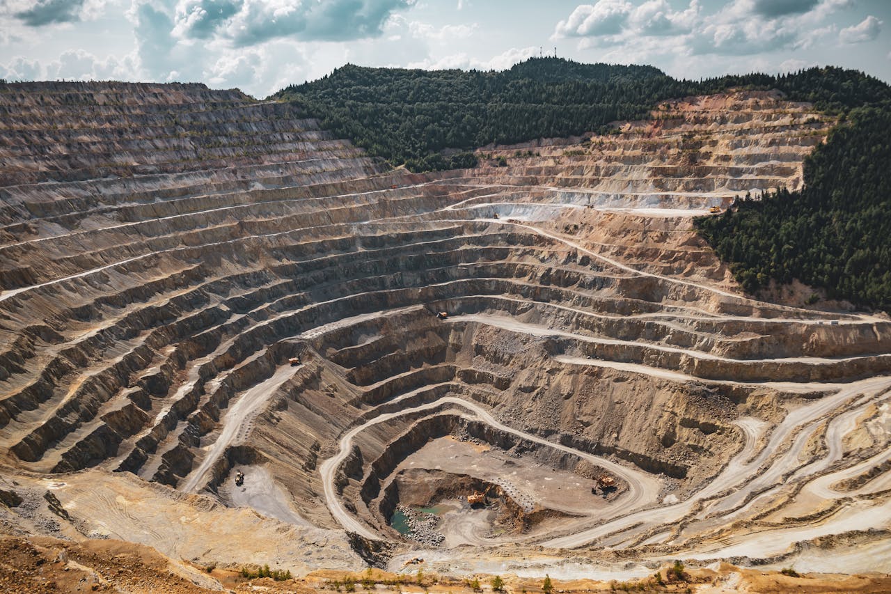 why-choose-us Aerial view of a large open-pit mine with terraced excavation during summer.