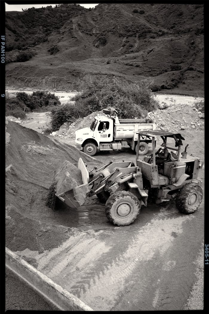 about-img Excavator and dump truck working in a quarry on a clear day.